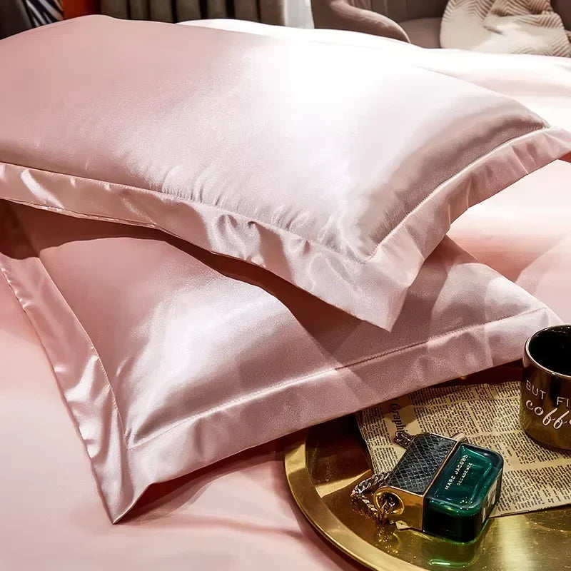 Pink smooth satin-feel pillowcase set folded on a bed