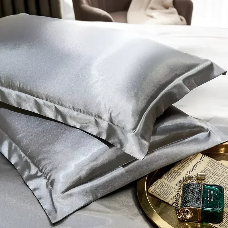 Grey smooth satin-feel pillowcase set stacked on white bedding