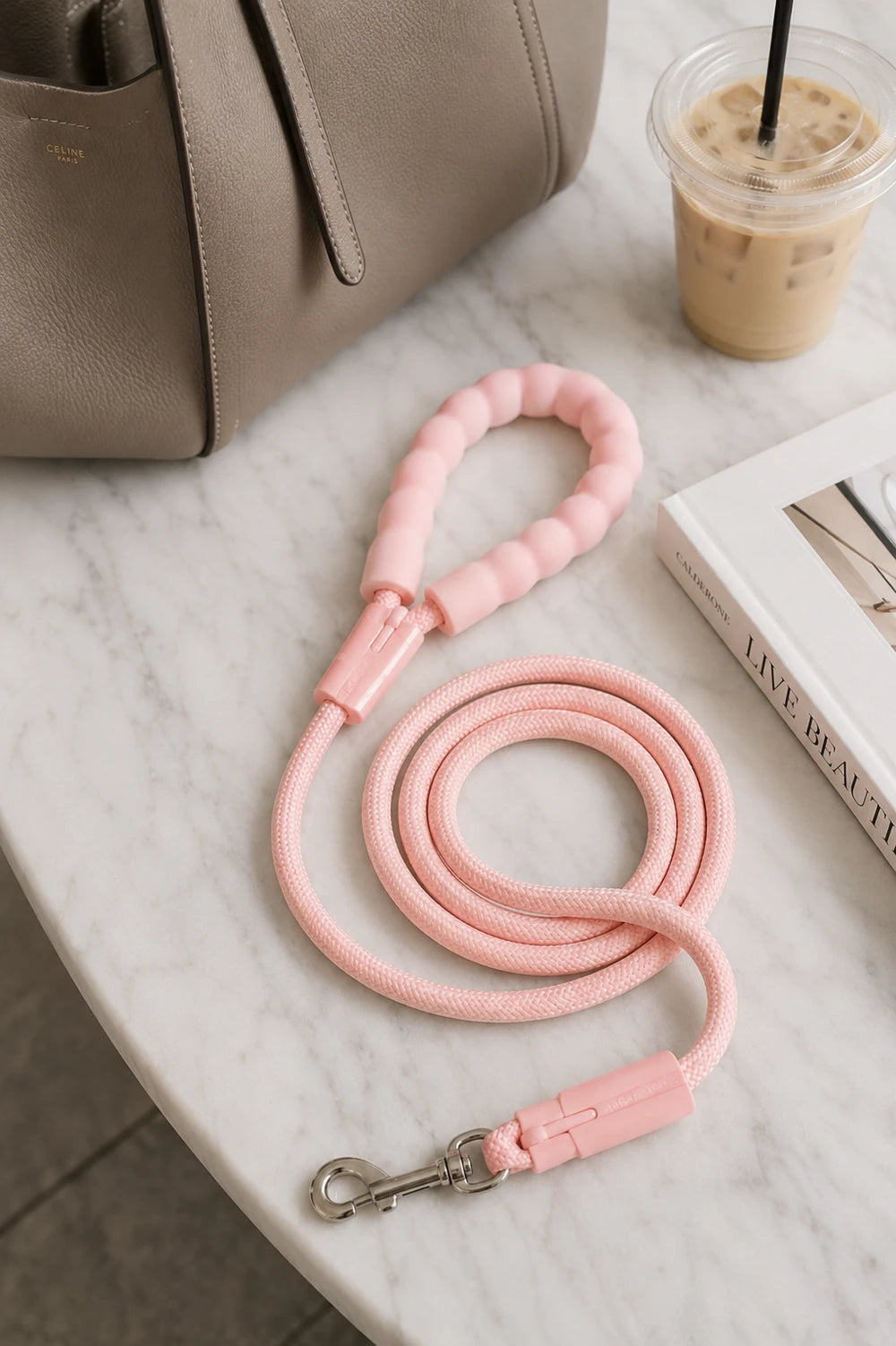 Pink rope dog leash with padded handle and metal clasp on a marble tabletop